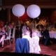 Brautpaar bei einer Hochzeit sitzt auf Stühlen mit 2 großen Luftballons zum Thema Wann ist der beste Zeitpunkt, um einen DJ für die Hochzeit zu buchen?